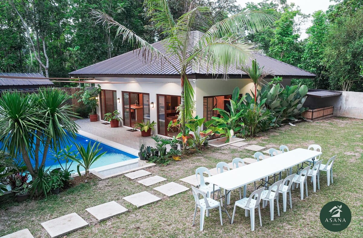 Villa exterior at dusk, with the pool and an outdoor dining table set for a group