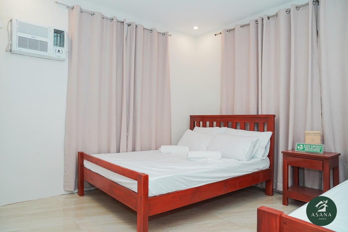 Bedroom with a red wood bed frame, curtains, and air conditioning