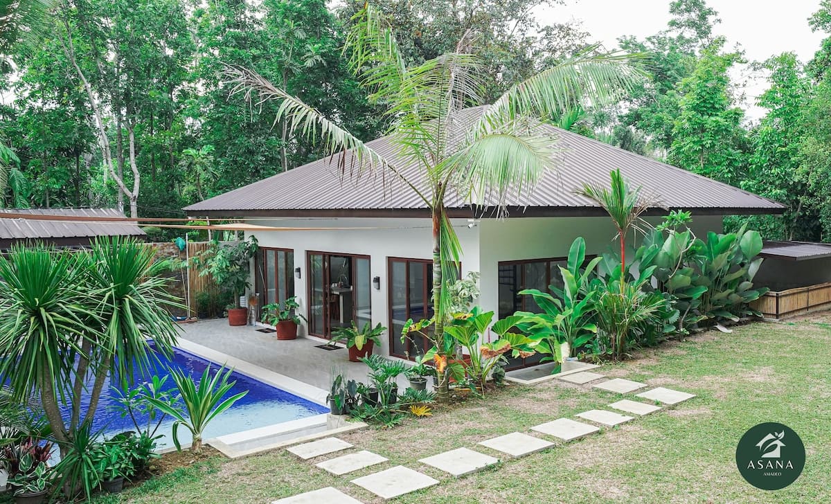 Villa exterior at dusk with palm trees framing the roofline