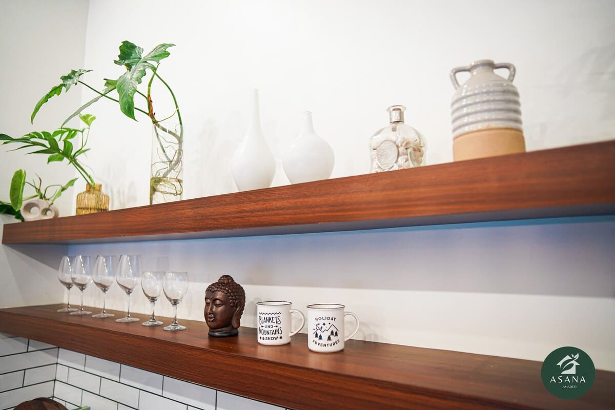 Open shelving with vases, glassware, plants, and a small Buddha head