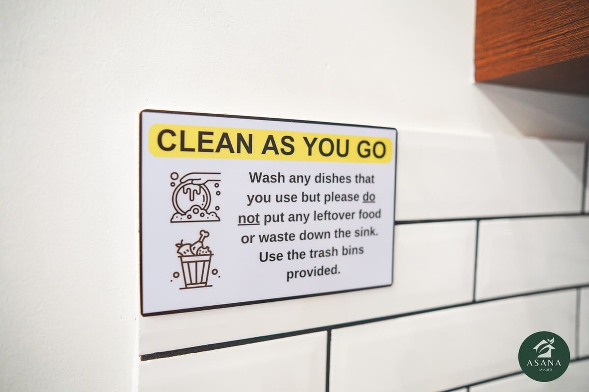 A "Clean As You Go" reminder sign in the kitchen