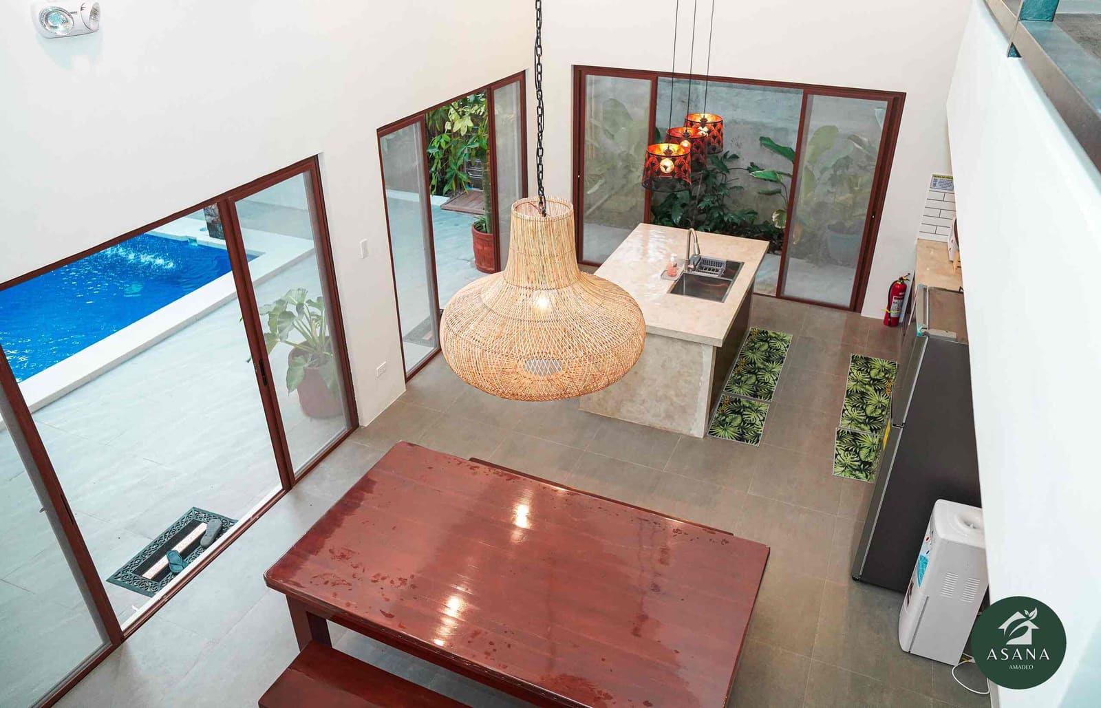 Aerial view from the loft looking down on the dining table, kitchen island, and pool beyond