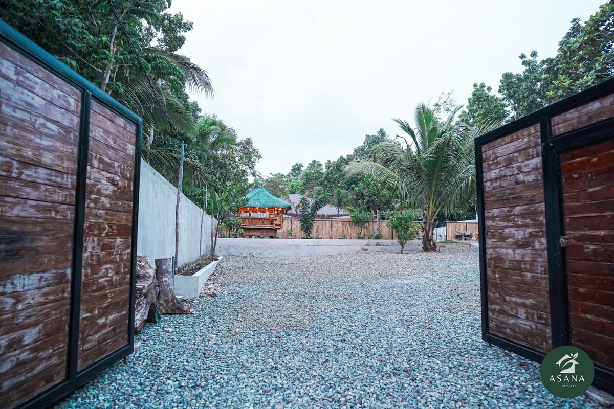 Gravel driveway and gate entrance to the villa, with the kubo visible beyond