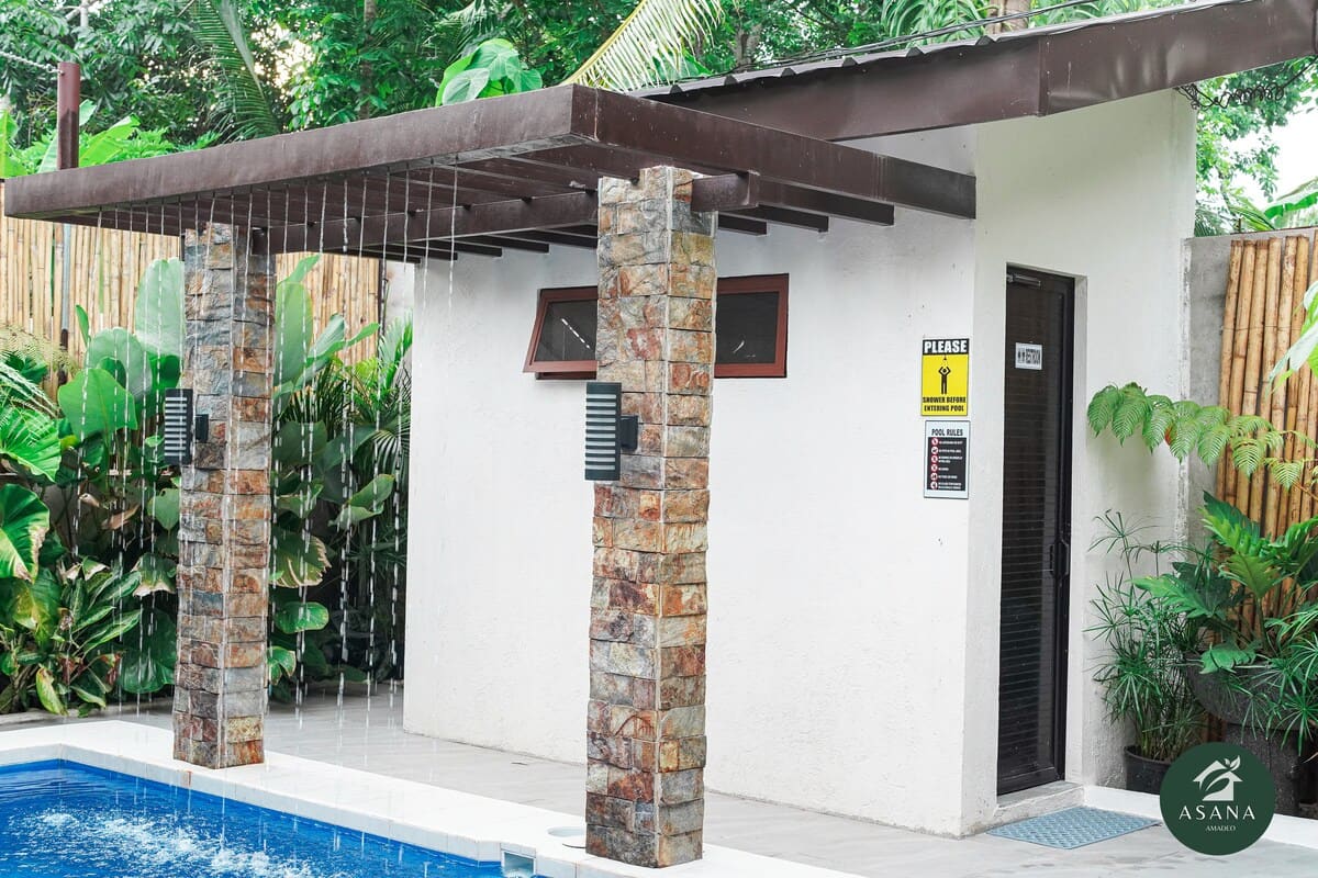 Outdoor rain shower with stone columns, next to the pool