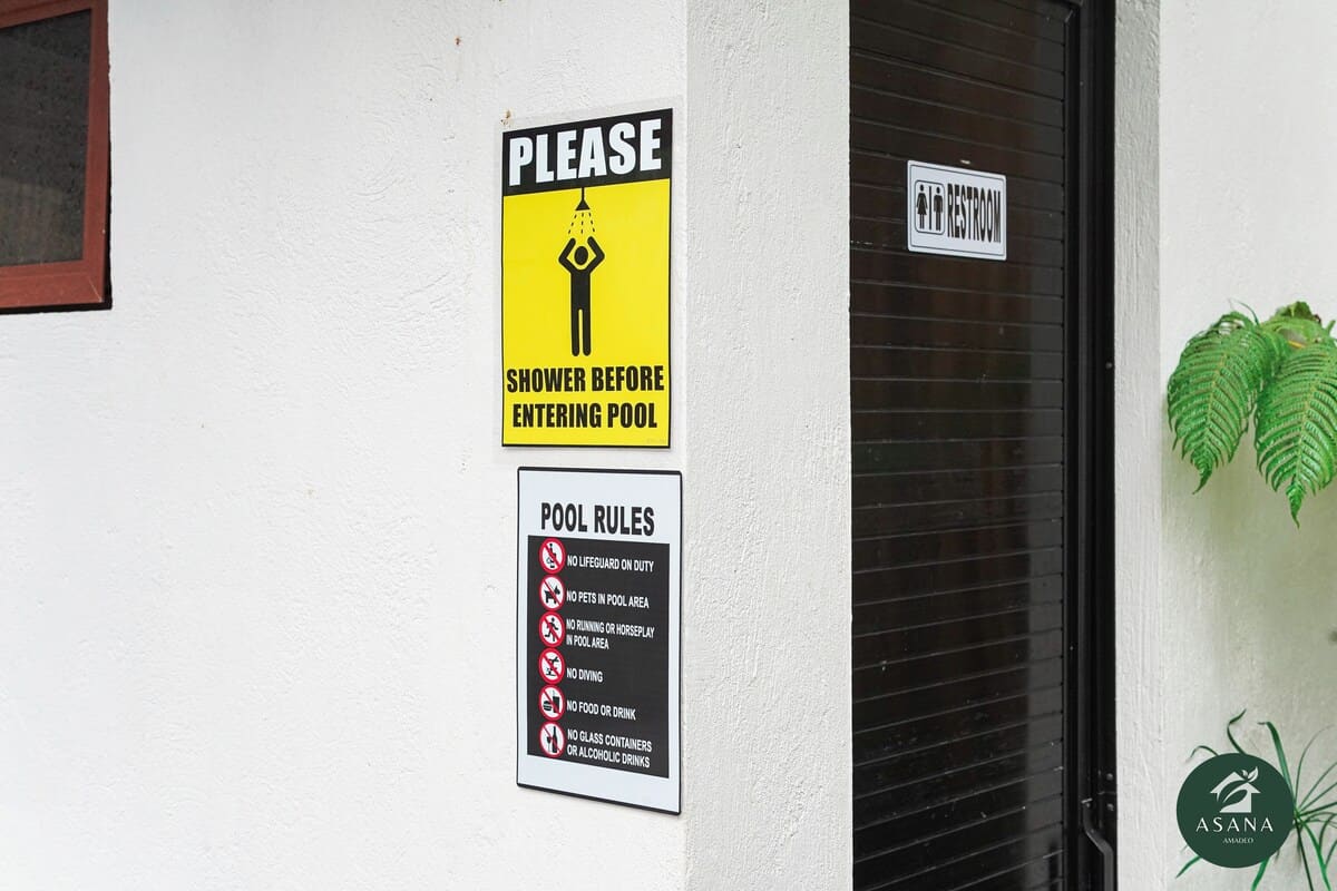 Pool rules and shower reminder signage by the pool entrance